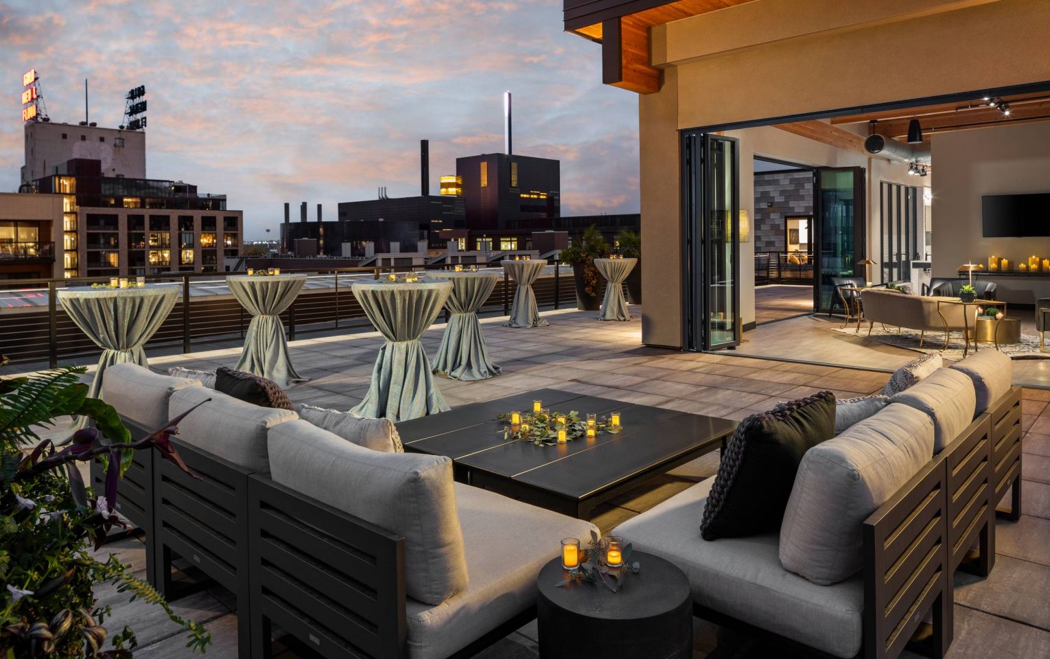 The JI Case rooftop terrace is set for a night event, with stylish draped tables and a city skyline under a twilight sky.